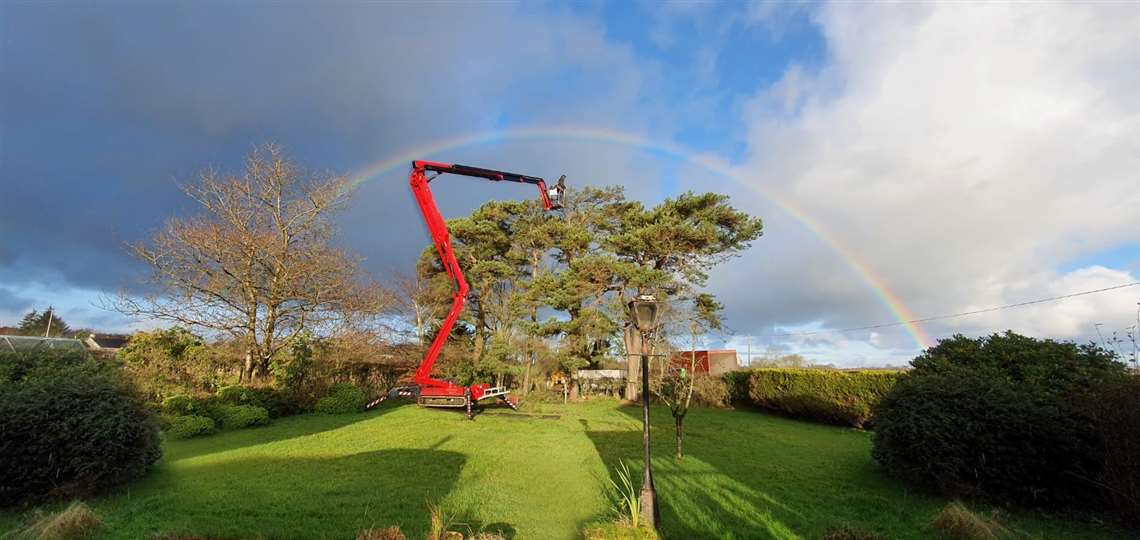 Tree surgeon Ian McClelland in the basket of his Hinowa Lightlift 26.14 Performance IIIS spider platform with the rainbow above him.