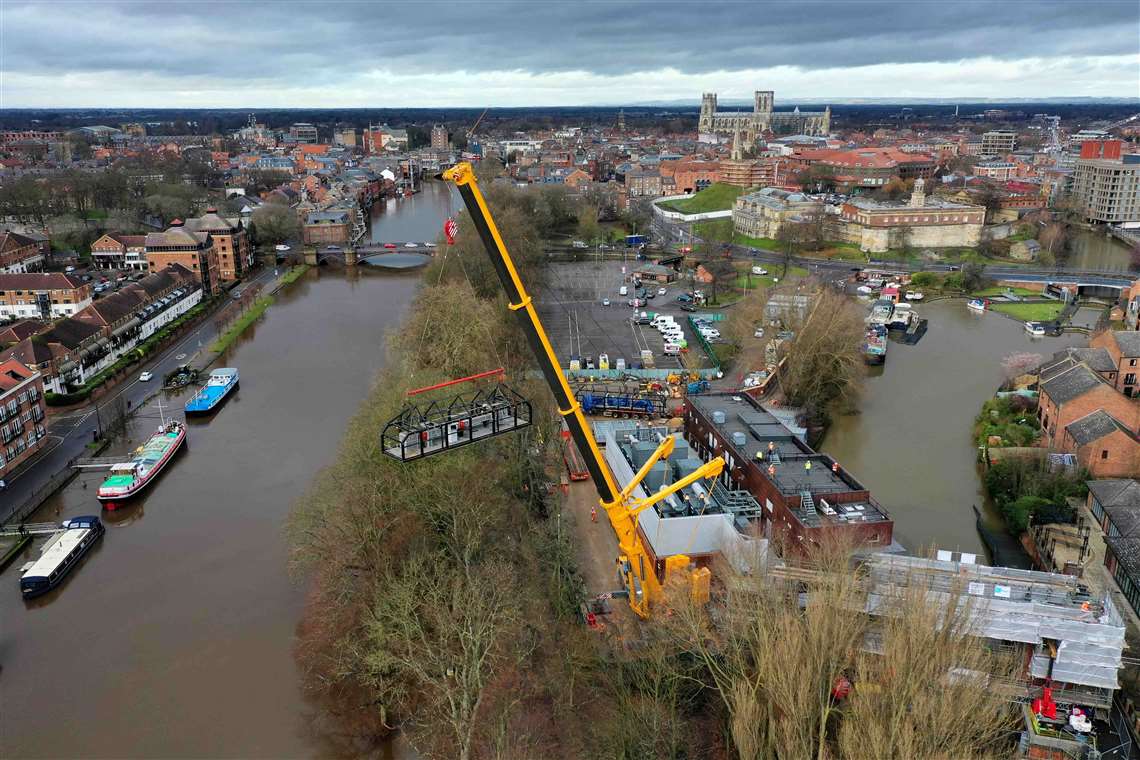 Aerial view of yellow Ainscough Liebherr boom up in flooded area