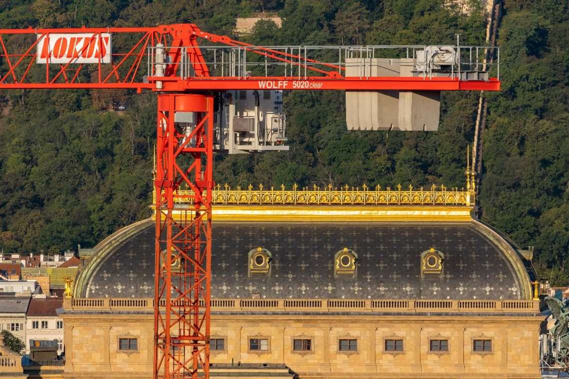 Red Wolff flat top tower crane in the Lokus fleet in sunshine in front of an old building