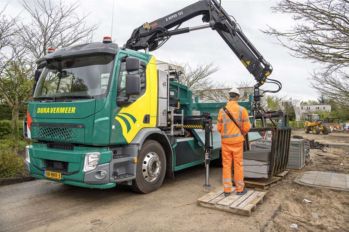 Green and yellow Volvo tipper truck with black Hiab loader crane and brick grab