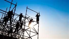 Construction workers erect scaffolding. (Image: Adobe Stock)