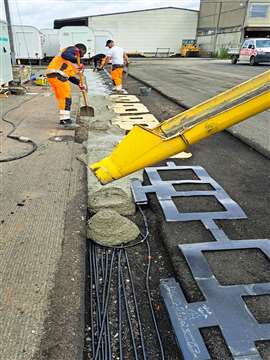 Workers lay asphalt over copper coils (Image: Strabag)