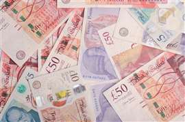 A collection of pound sterling bank notes laid out on a flat surface.
