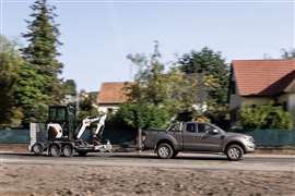A Bobcat E16 mini excavator is transported on a trailer