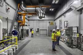 An interior view of the genset test cell featuring a diesel fuel skid, localised control panels, and an adjustable engine exhaust arm