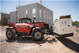 A construction telehandler positions a genset on a construction site