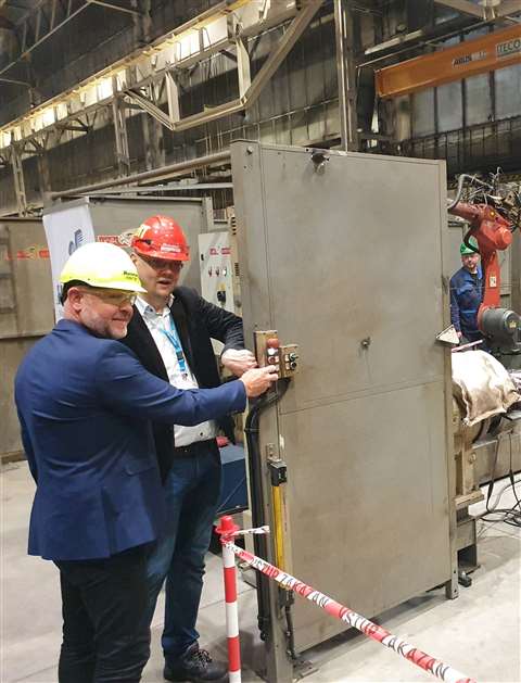 Two men in suits and hardhats standing with a piece of steel