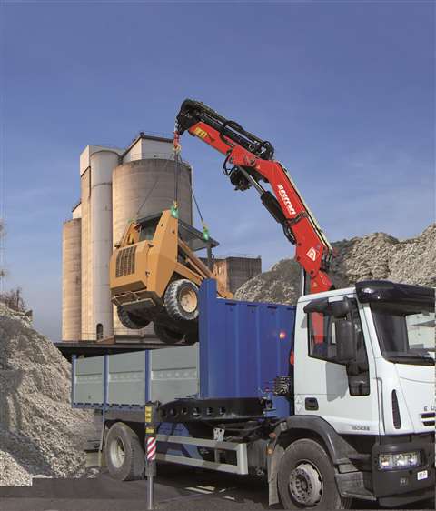 Red crane lifting a yellow machine onto a blue and white truck