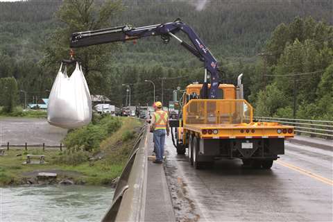 black crane on orange truck carrying a 1 tone dumpy bag