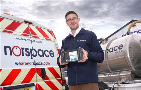 An employee holds a tablet with the Norspace logo shown