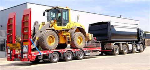 red Nooteboom plant trailer loaded with a machine and hitched to a tipper truck