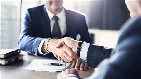 Two people shake hands at a meeting