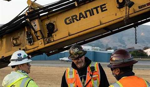 Three Granite Construction workers stand on a construction site