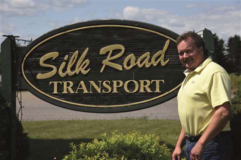Todd Haraty, COO at Silk Road Transport standing by a company sign