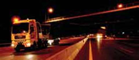 Straddling the concrete divider between carriageways the convoy makes its way under a bridge with th