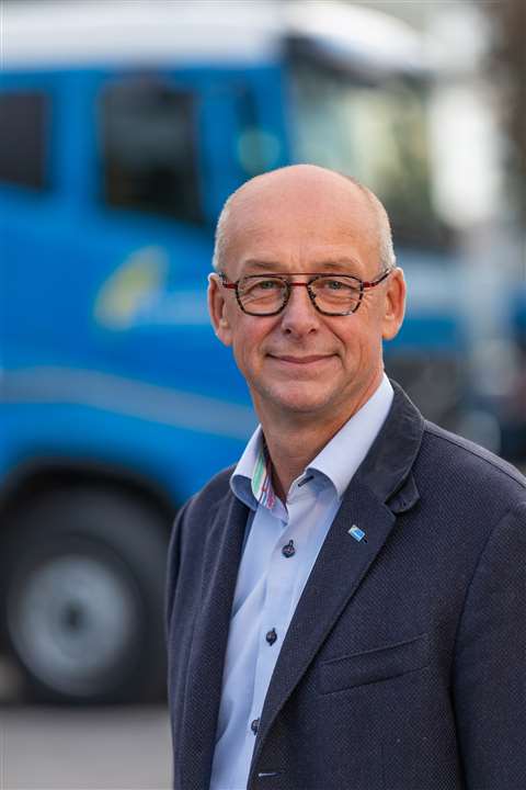 Kees Kompier stood in front of a blue and white truck, glasses, short grey hair, 53 years old