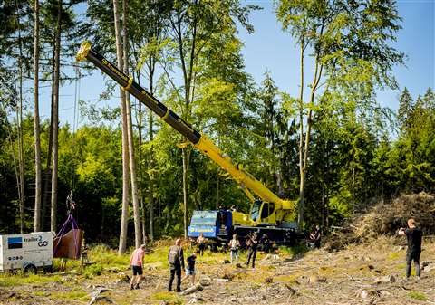 ESB's Liebherr LTM 1050-3.1 at work on set. Yellow and blue AT crane lifting a grand piano out of the back of a van in the middle of a forest