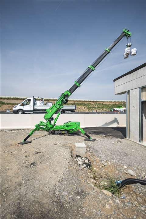 Side view of bright green Palazzani RPG2900 mini crane fully extended and placing a load on a rooftop