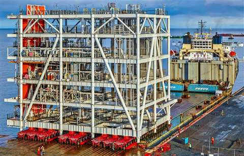Mammoet-Haisla Joint Venture offloading grey steel empty pipe racks from a red heavy lift vessel
